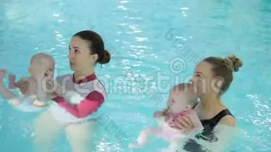 游泳课。 在游泳池里教婴儿游泳的母亲